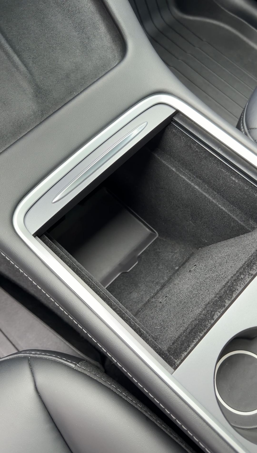 Open centre console storage bin of a Tesla Model Y after cleaning.