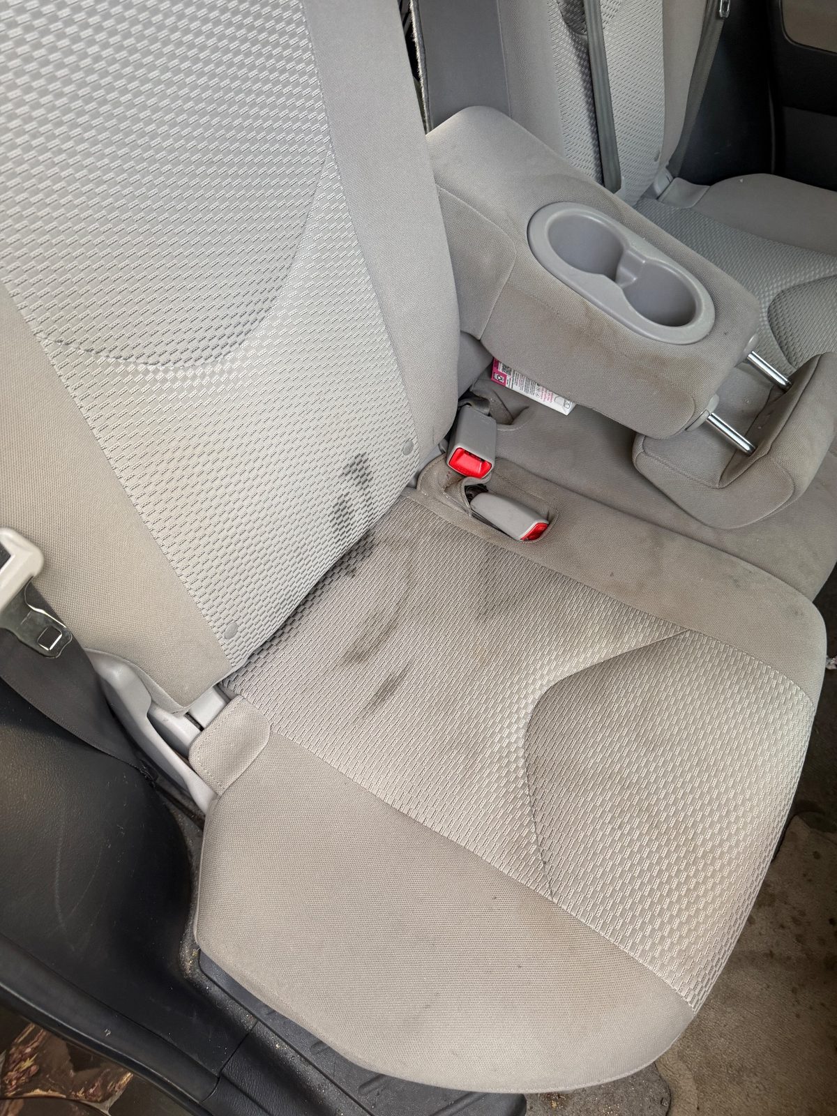 Rear bench seat of a 2011 Toyota RAV4 before detailing, dark stains on the cloth