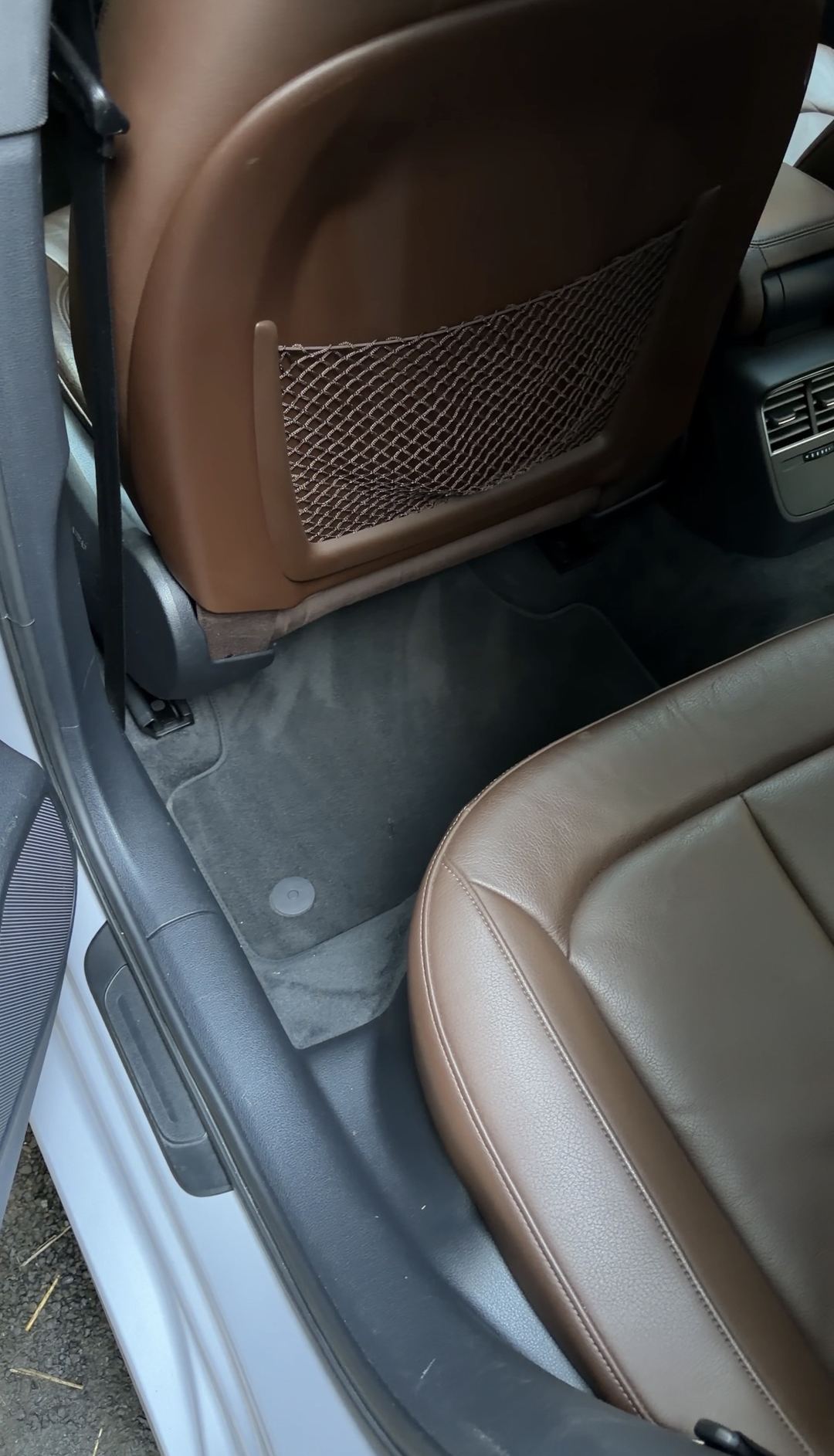 Vacuumed rear floor mat behind the driver seat of an Audi A3 with brown leather seats