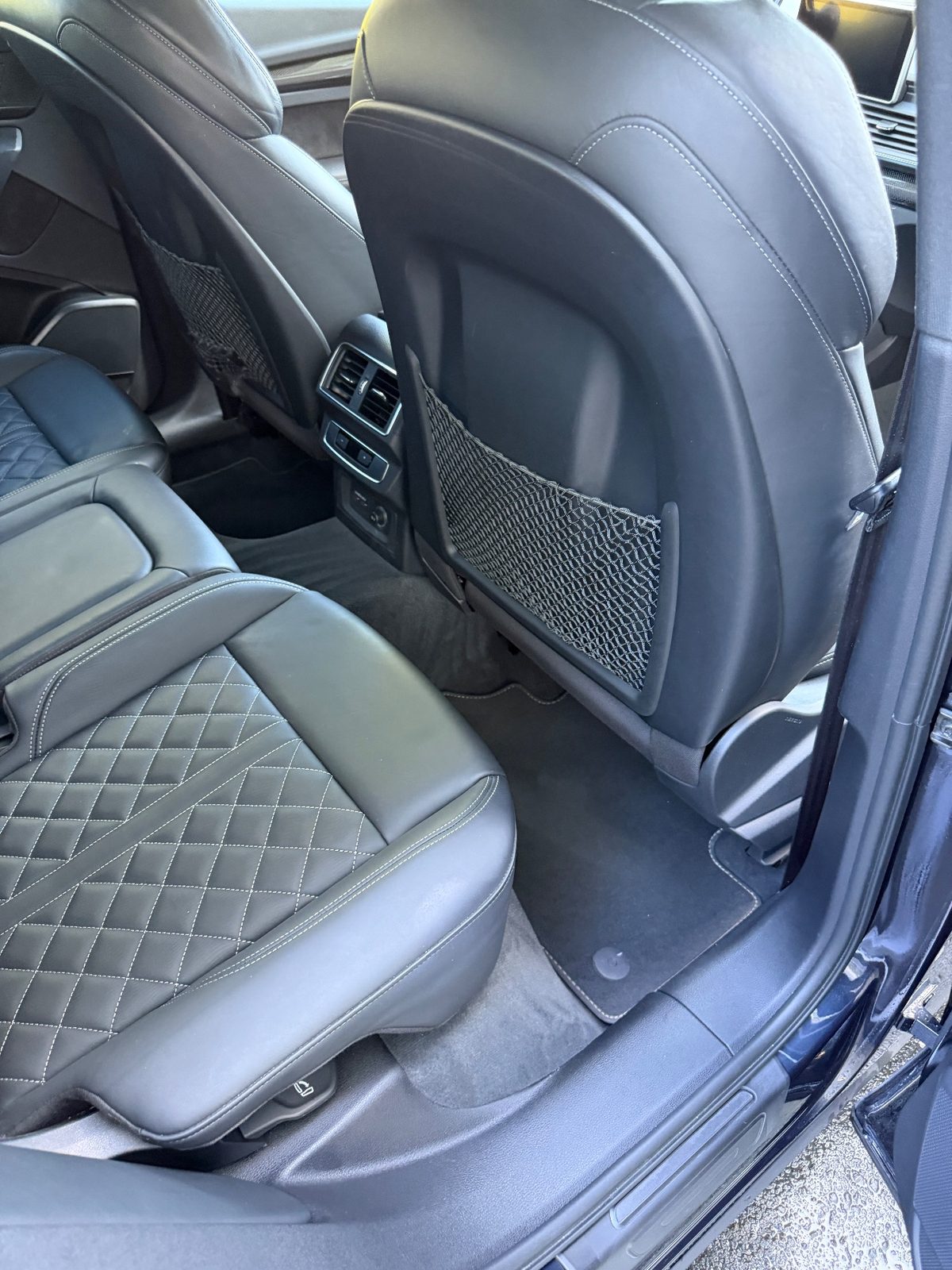 Rear-right footwell of an Audi SQ5 after vacuuming, with a clean mat and leather