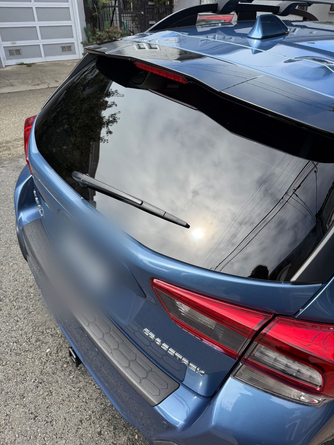 Clean rear hatch and gloss-black spoiler of a blue Subaru Crosstrek after washing