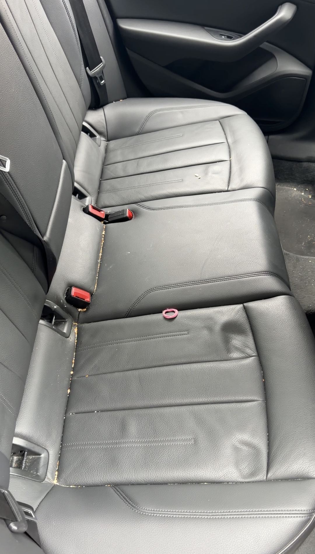 Crumbs along the seat crease of the black leather rear bench in an Audi A4
