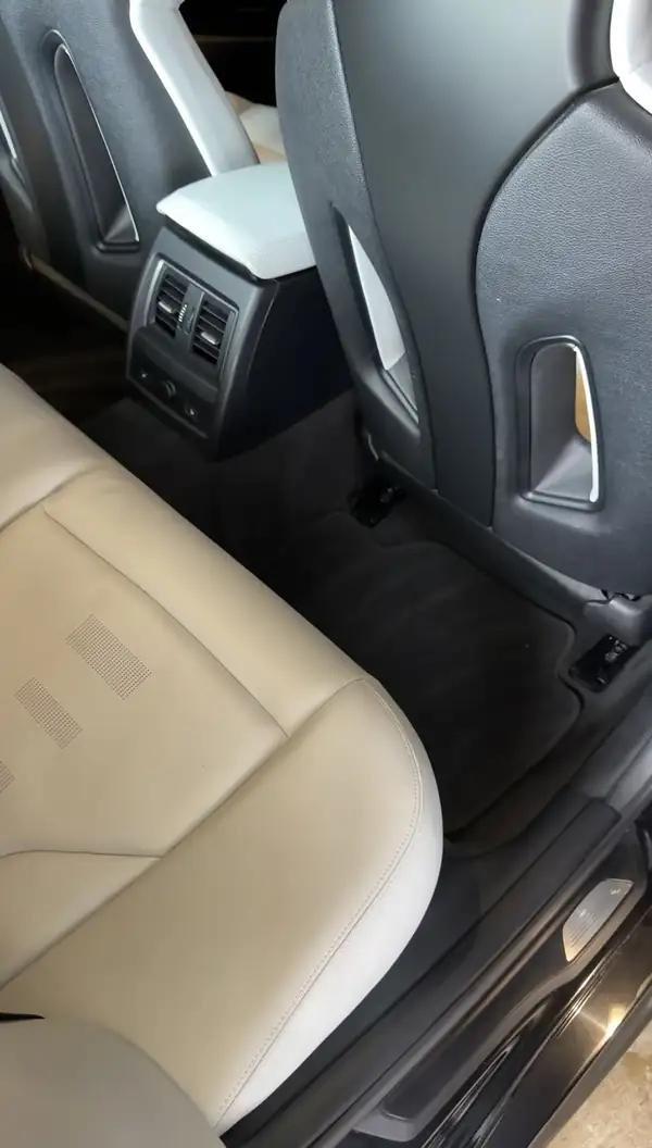 Cleaned rear seat and footwell of a BMW M3, white leather bench above a groomed black floor mat