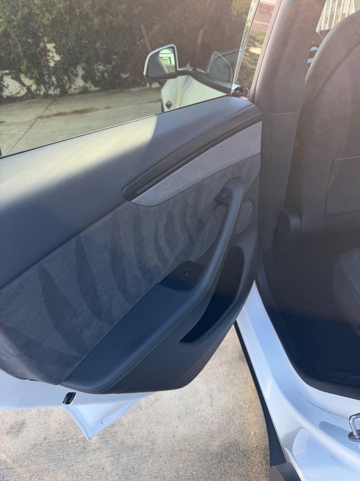 Clean rear door panel of a white Tesla Model Y after detailing