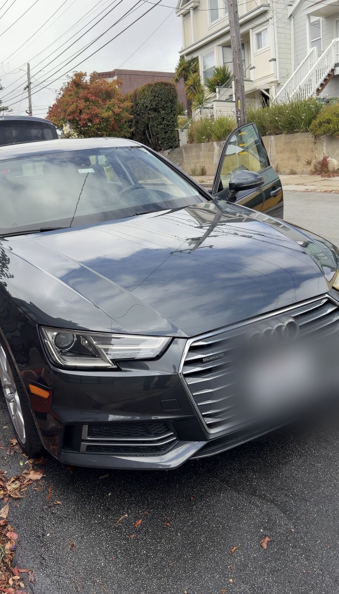 Freshly washed grey Audi A4 front with a glossy hood, still wet, on a residential street