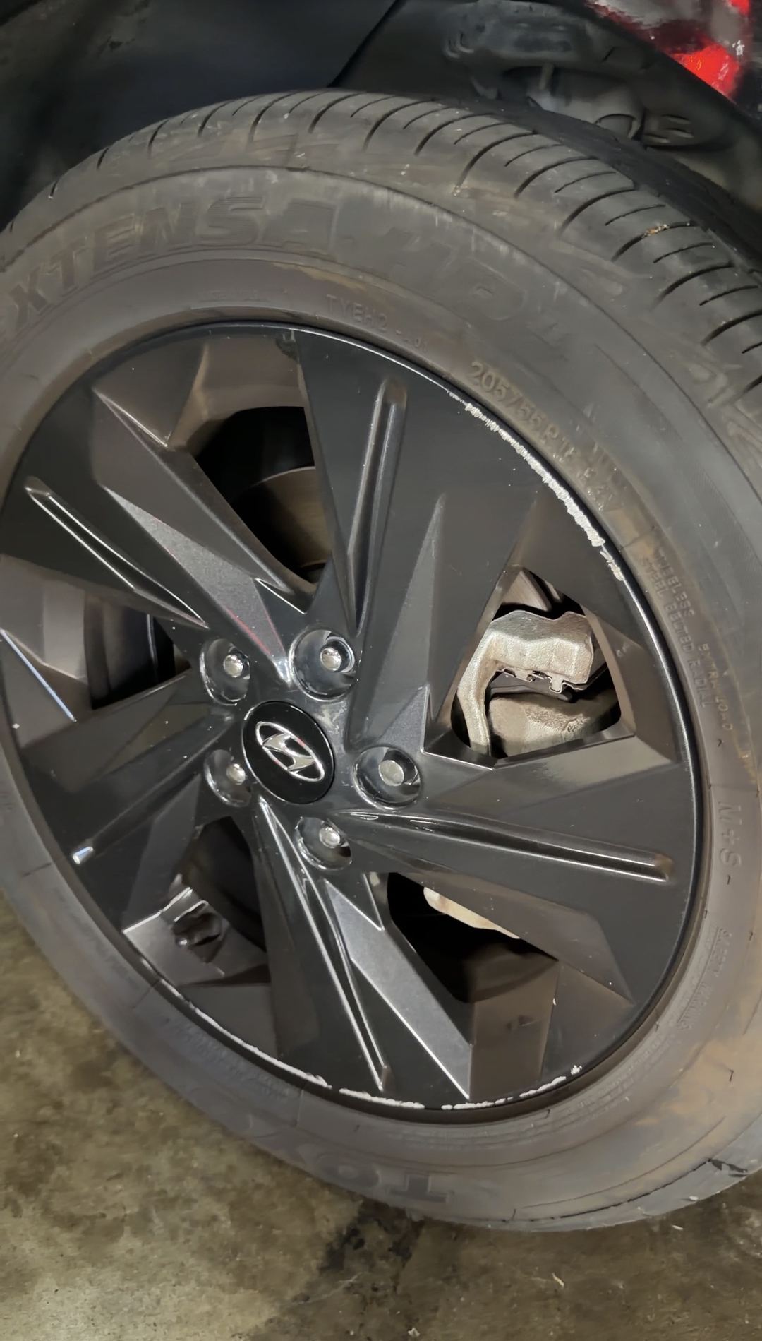 Dark grey alloy wheel and tyre on a black Hyundai Elantra in a parking garage