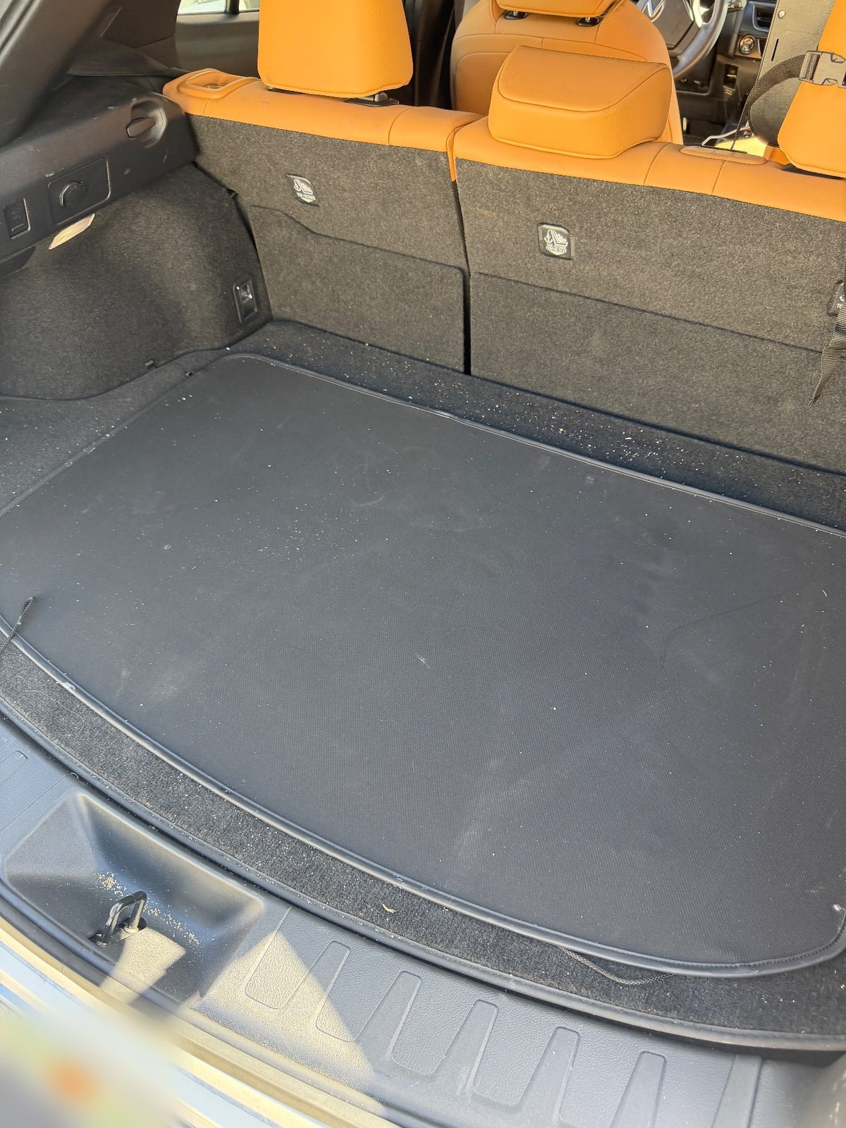 Cargo area of a white Lexus UX before detailing with grit and crumbs along the board edge