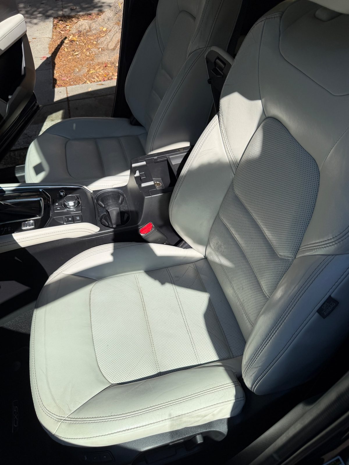 Clean driver seat of a dark blue Mazda CX-5 after detailing, cream leather free of marks