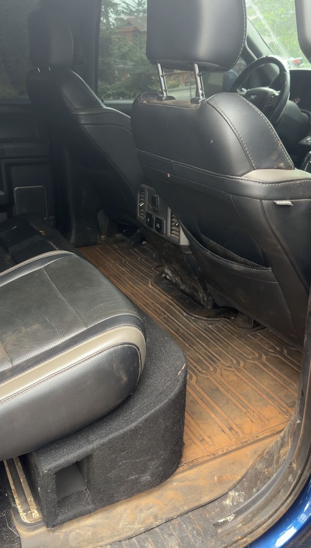 Rear floor of a Ford F-150 Raptor caked in dried mud before an interior detail