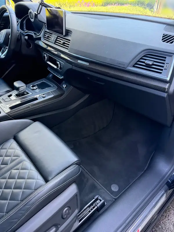Front passenger footwell of an Audi SQ5 after detailing, with a clean, vacuumed mat and wiped dash