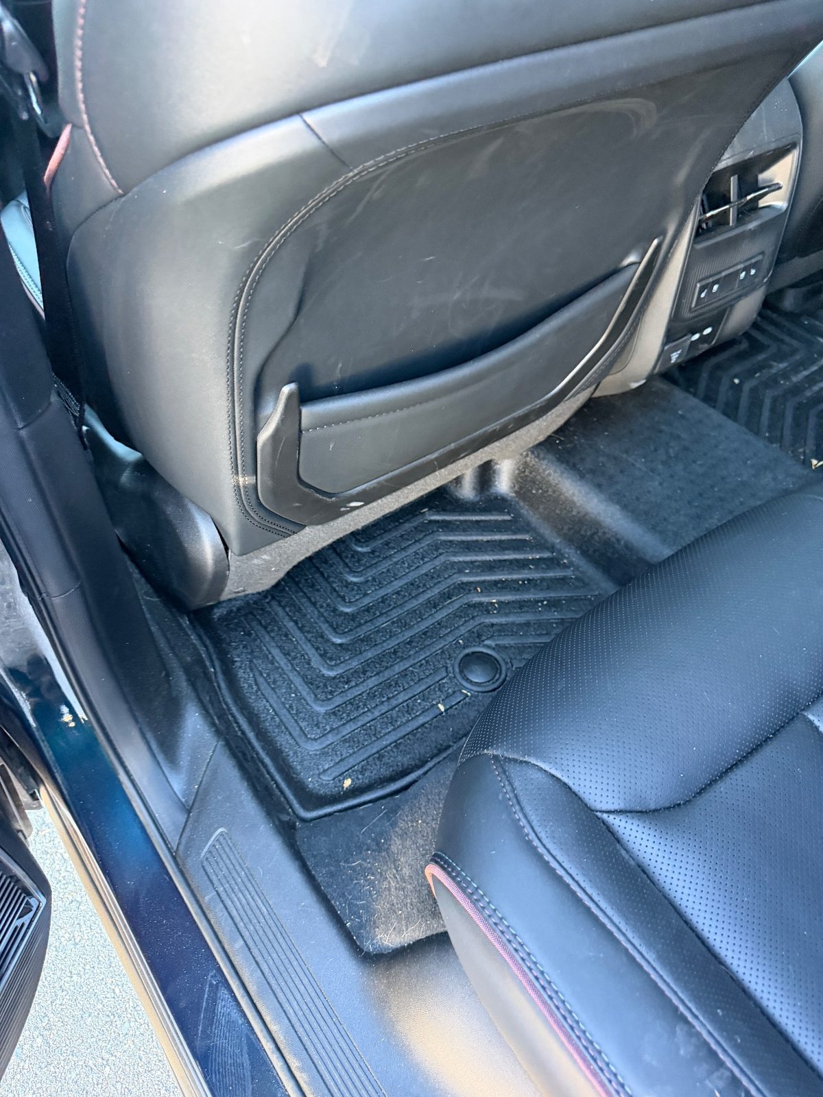 Rear footwell of a Jeep Wagoneer S before detailing, with hair and debris on the mat