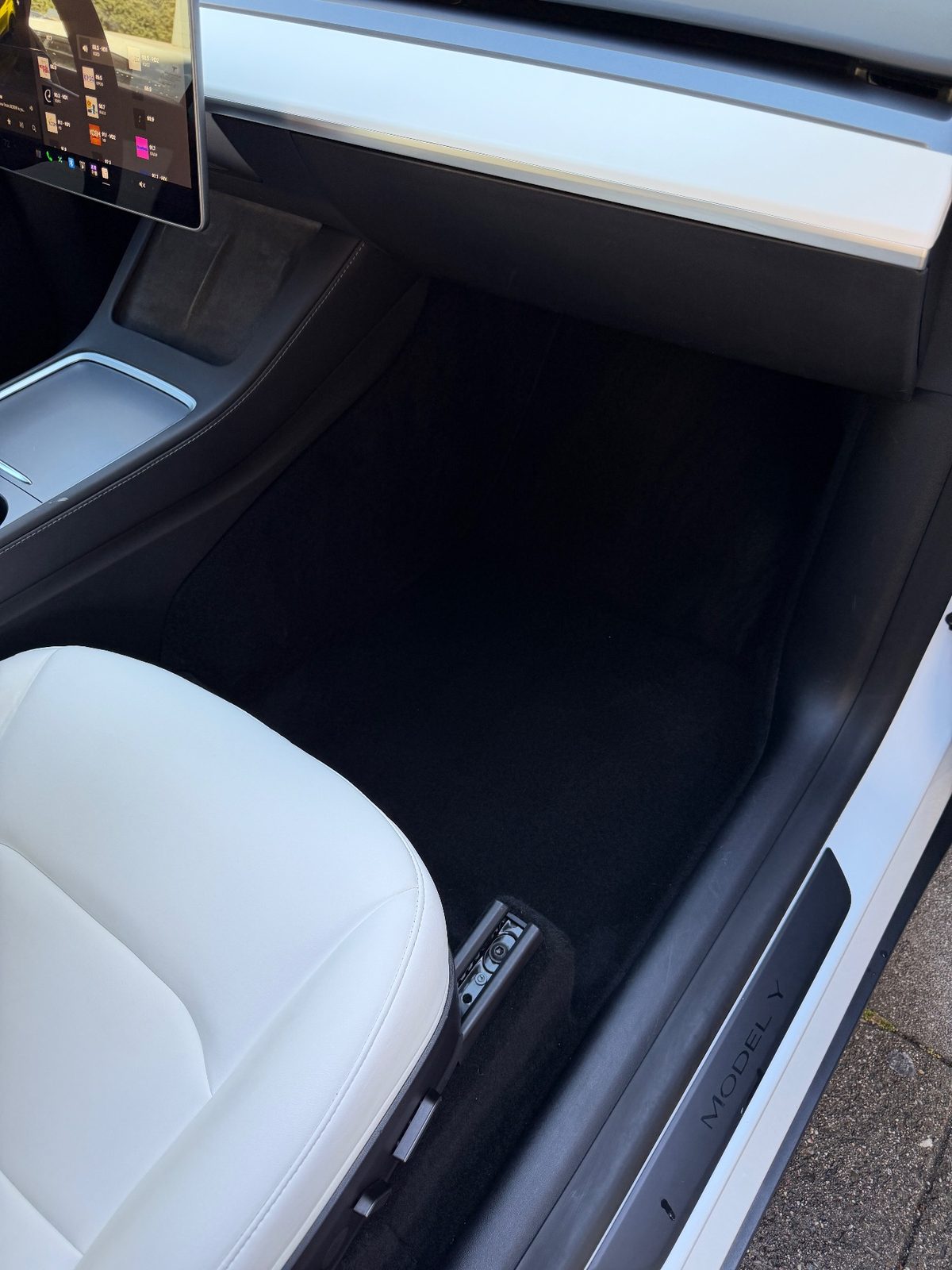 Clean passenger footwell of a Tesla Model Y after detailing