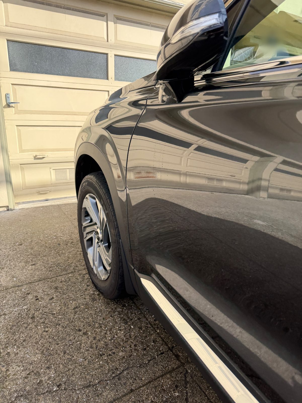 Gleaming driver-side front fender and door of a dark grey Hyundai Santa Fe after detailing