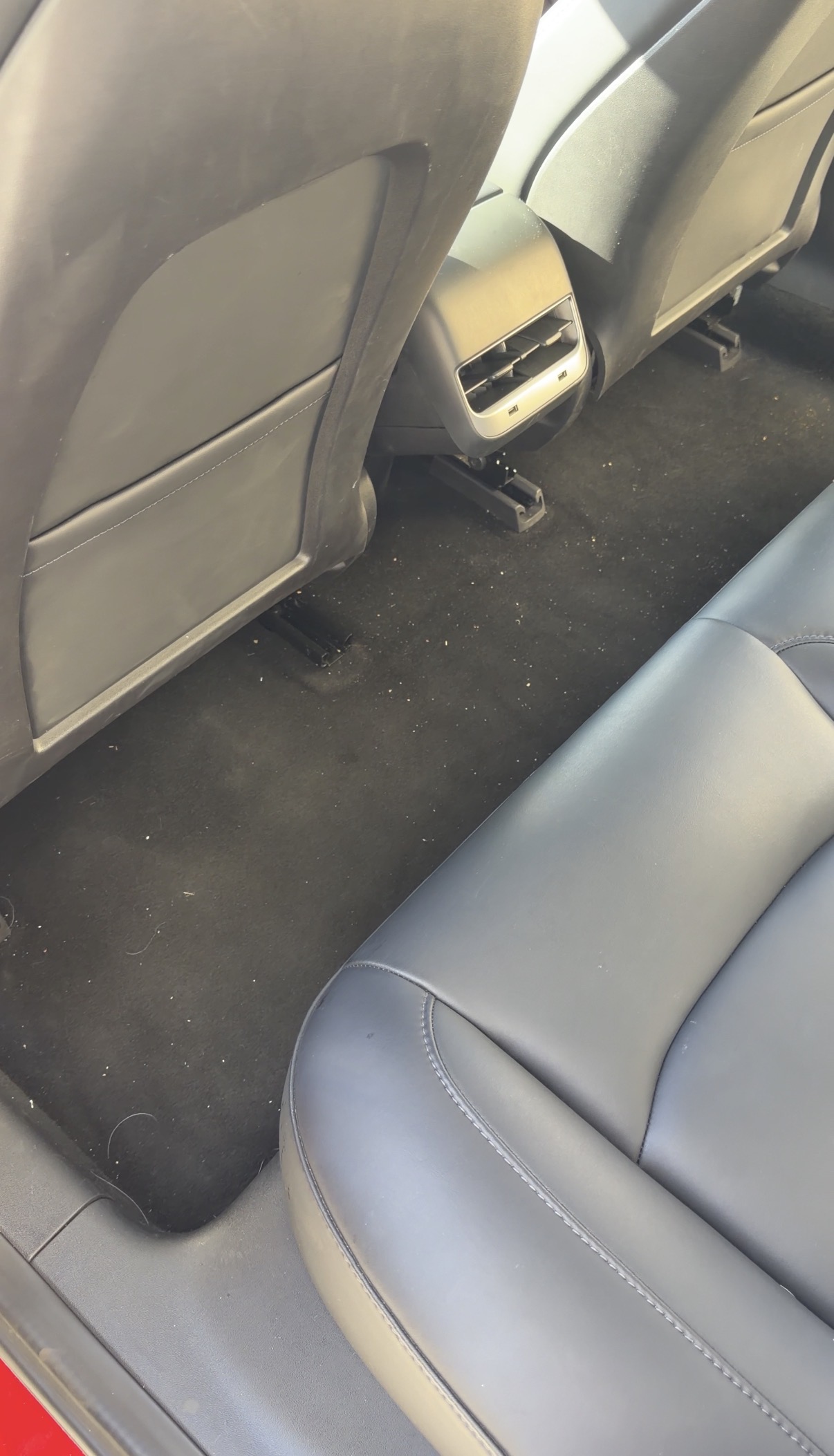 Tesla Model 3 rear seat floor before detailing, debris scattered