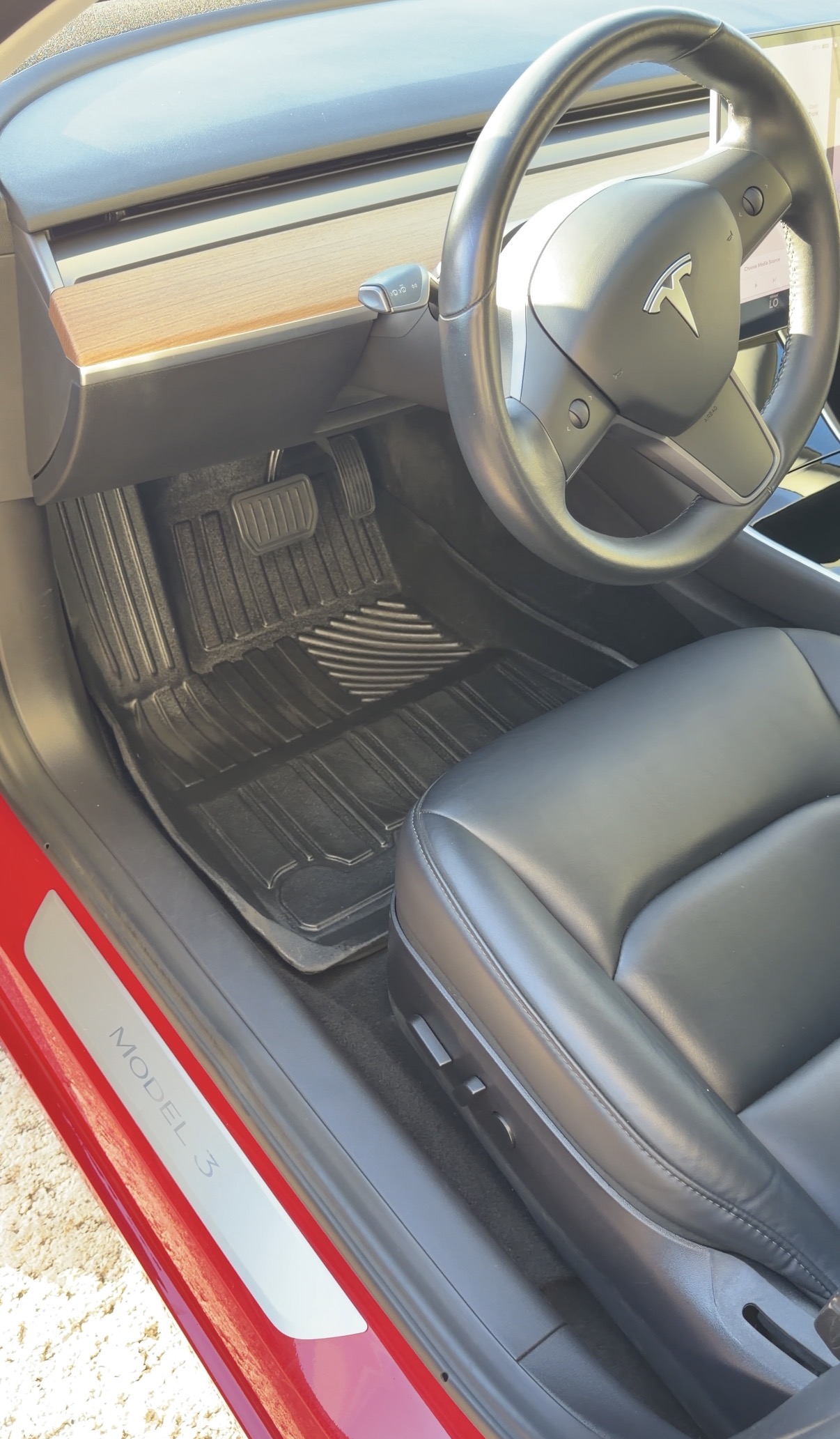 Tesla Model 3 driver footwell after detailing, clean floor mat with steering wheel visible