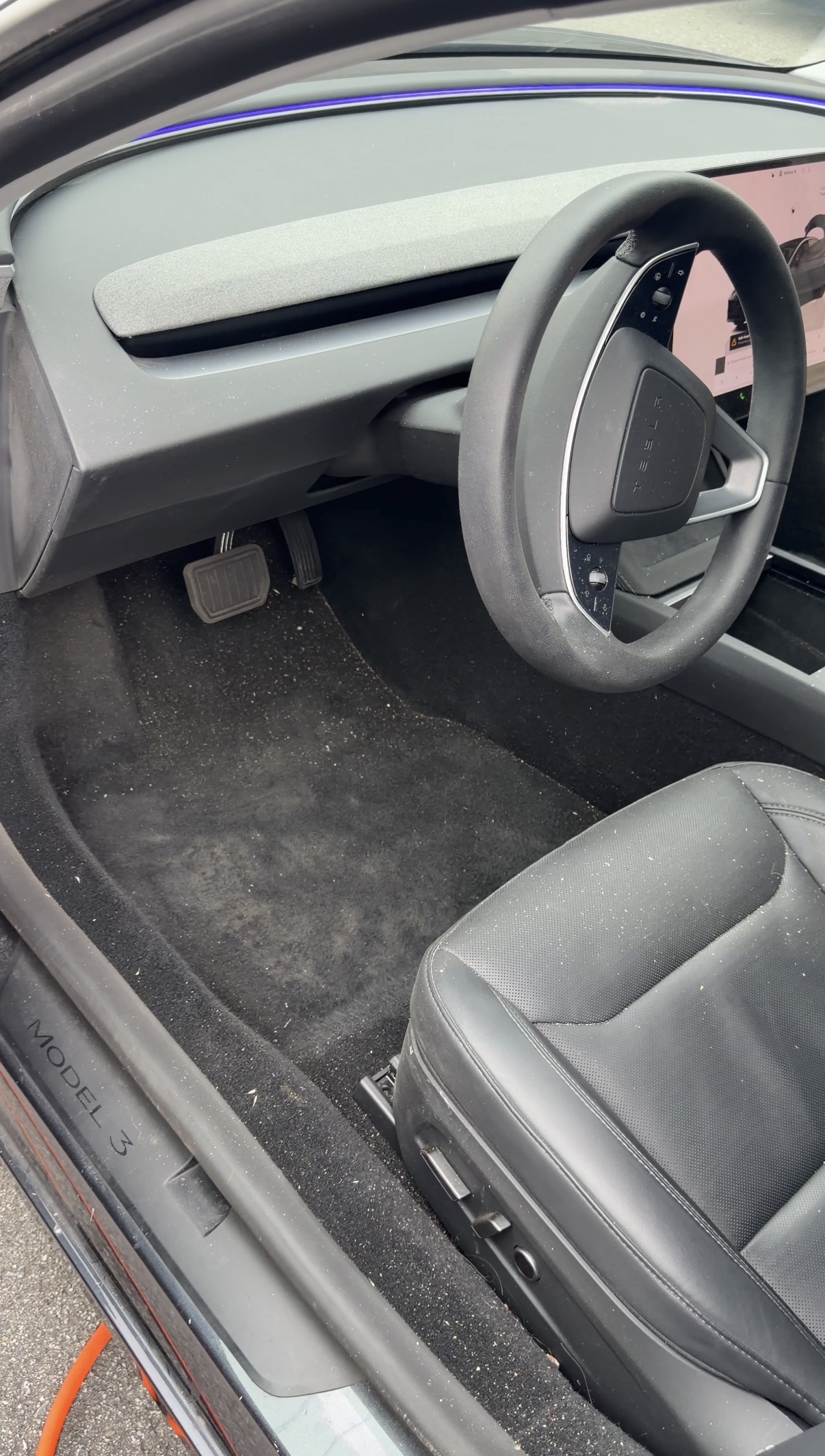 Tesla Model 3 driver footwell before detailing, dust and sand on carpet