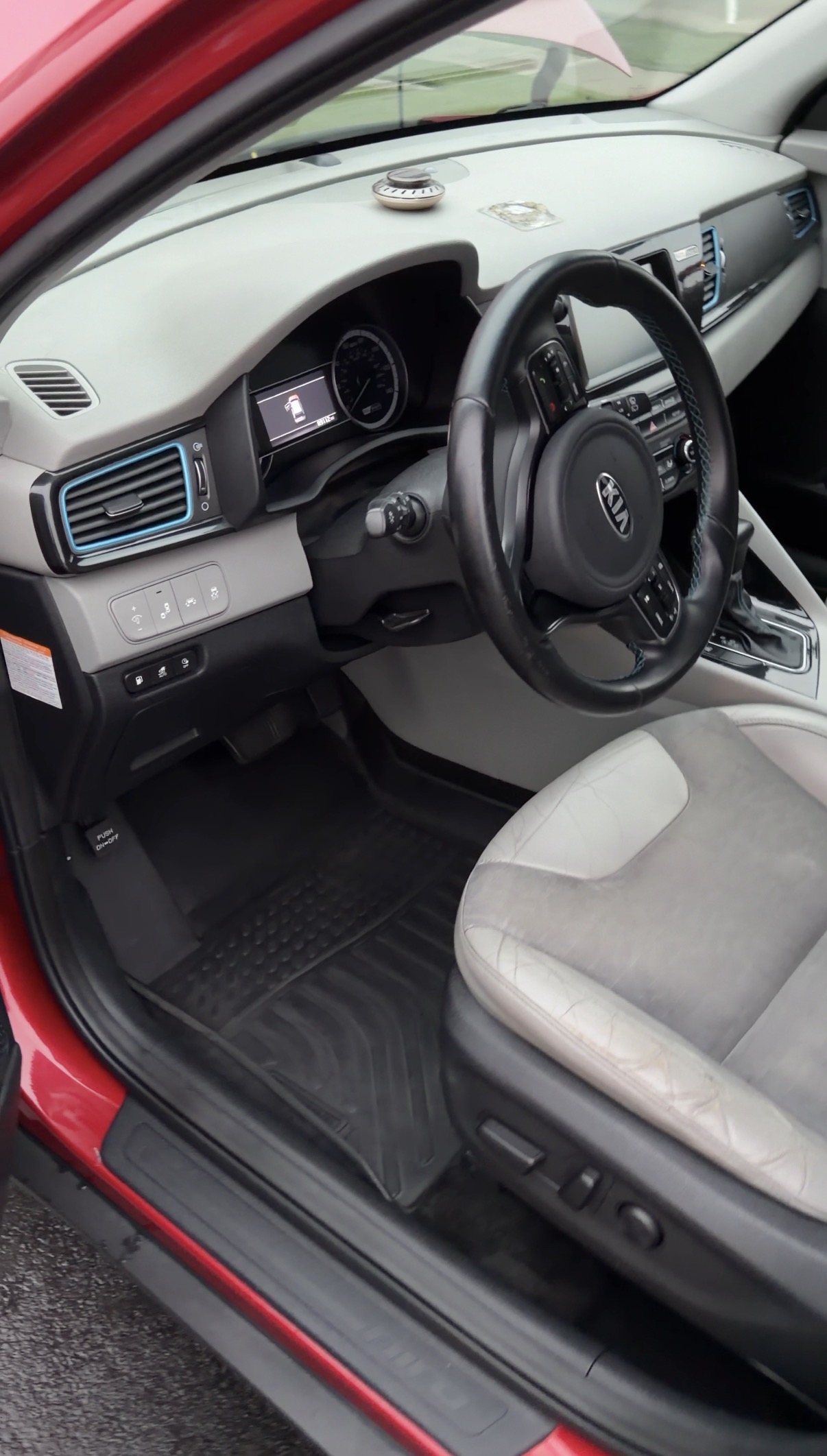 Clean front cabin of the Kia Niro after a mobile interior detail — dashboard, steering wheel, and floor mat