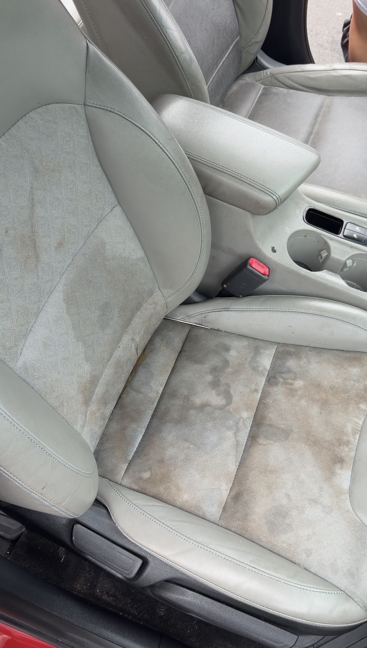 Kia Niro passenger seat and center console before detailing, with light debris around the cupholders