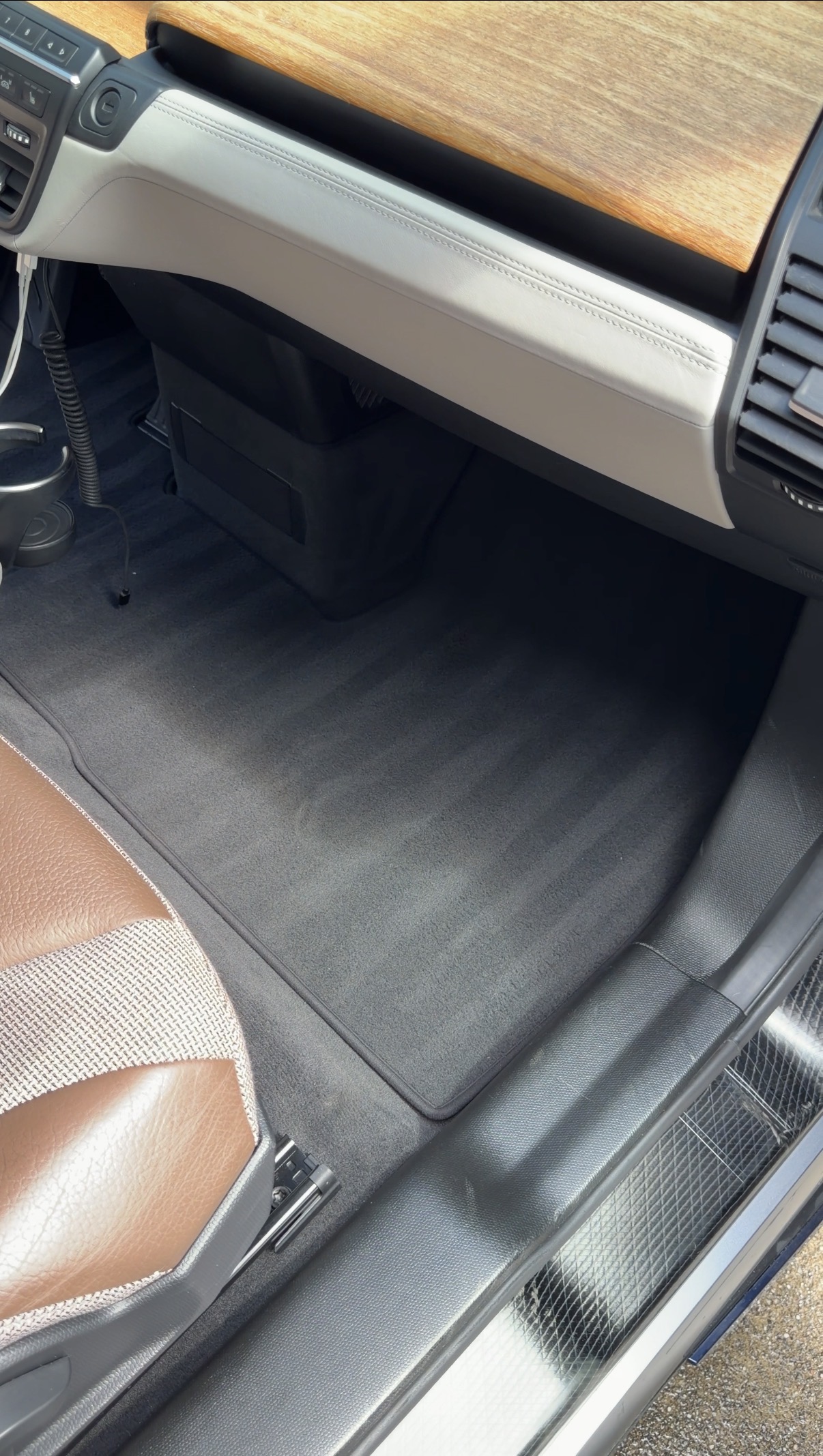 BMW i3 passenger footwell after detailing, clean carpet with wood dash trim visible