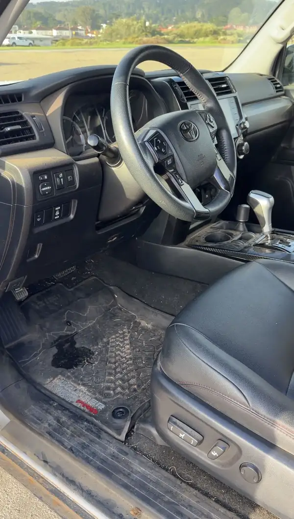 Driver seat area of a Toyota 4Runner with a wet, dirty TRD Pro floor mat and dusty sill