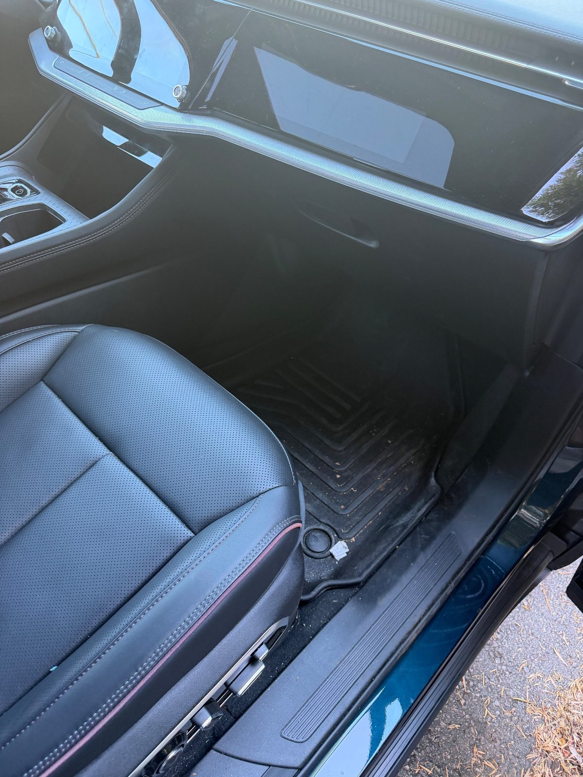 Passenger footwell of a Jeep Wagoneer S before detailing, with dirt on the floor mat
