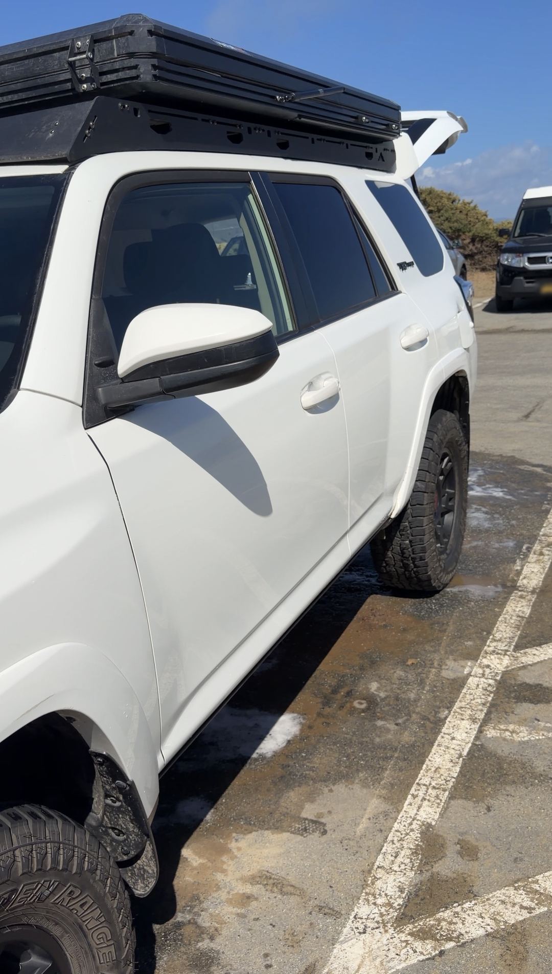 Driver side of a clean white Toyota 4Runner TRD Pro with a rooftop tent and black wheels