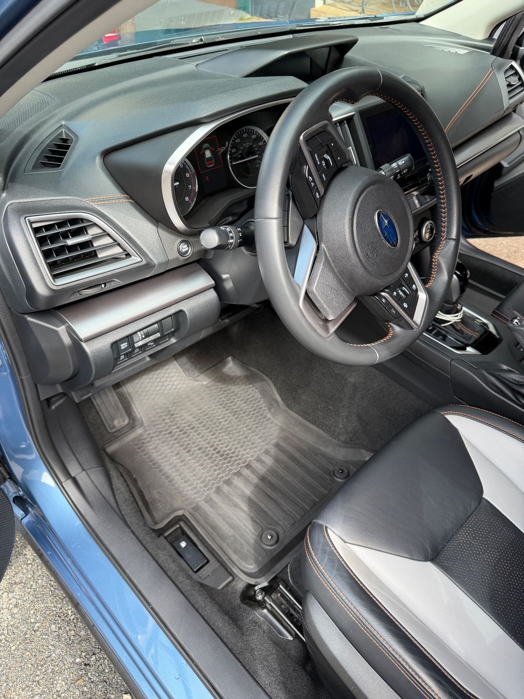 Clean driver footwell and dashboard of a Subaru Crosstrek after detailing, with the rubber floor mat back in place