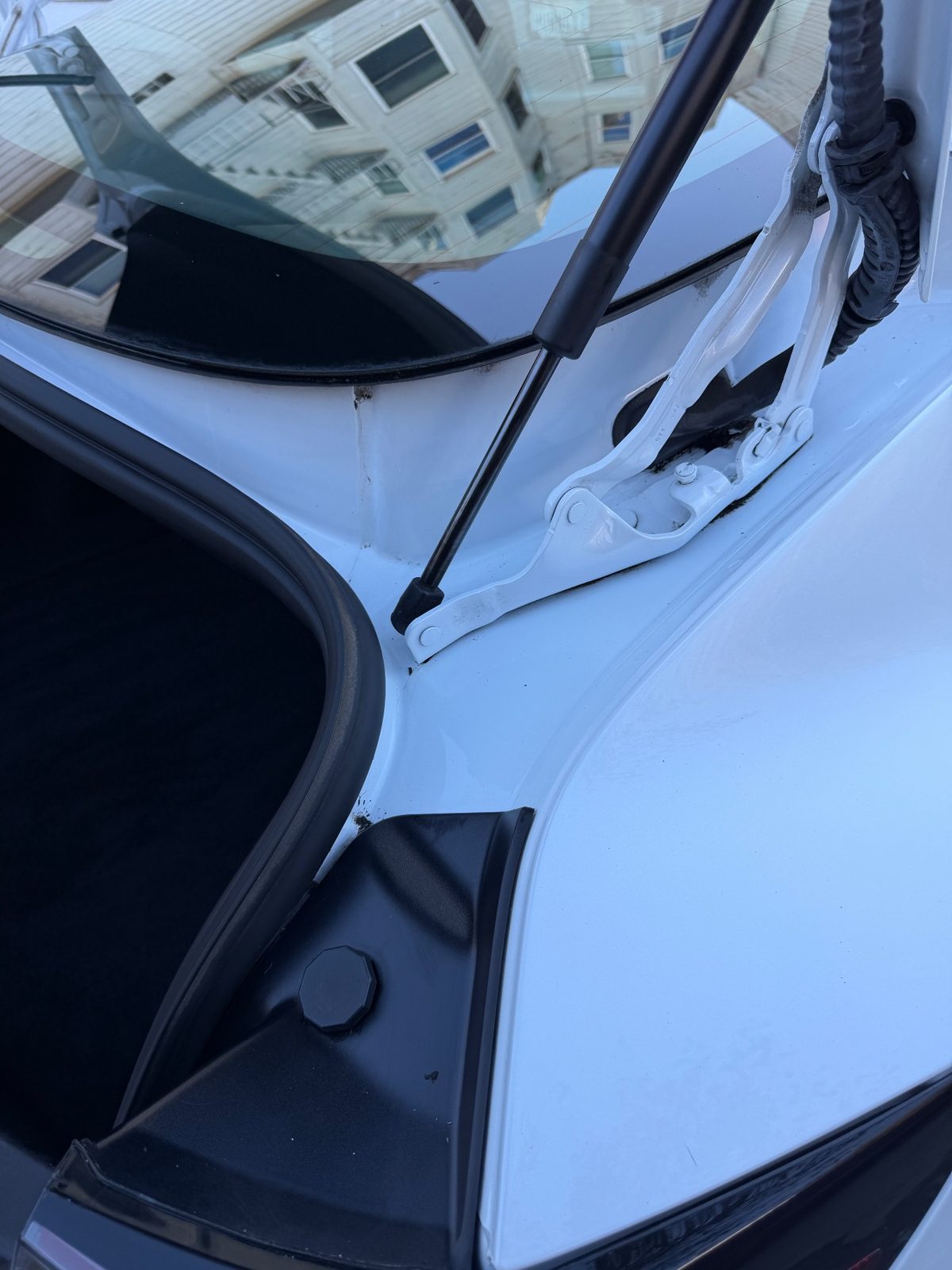 Clean boot hinge and seal channel on a white Tesla Model 3 after detailing