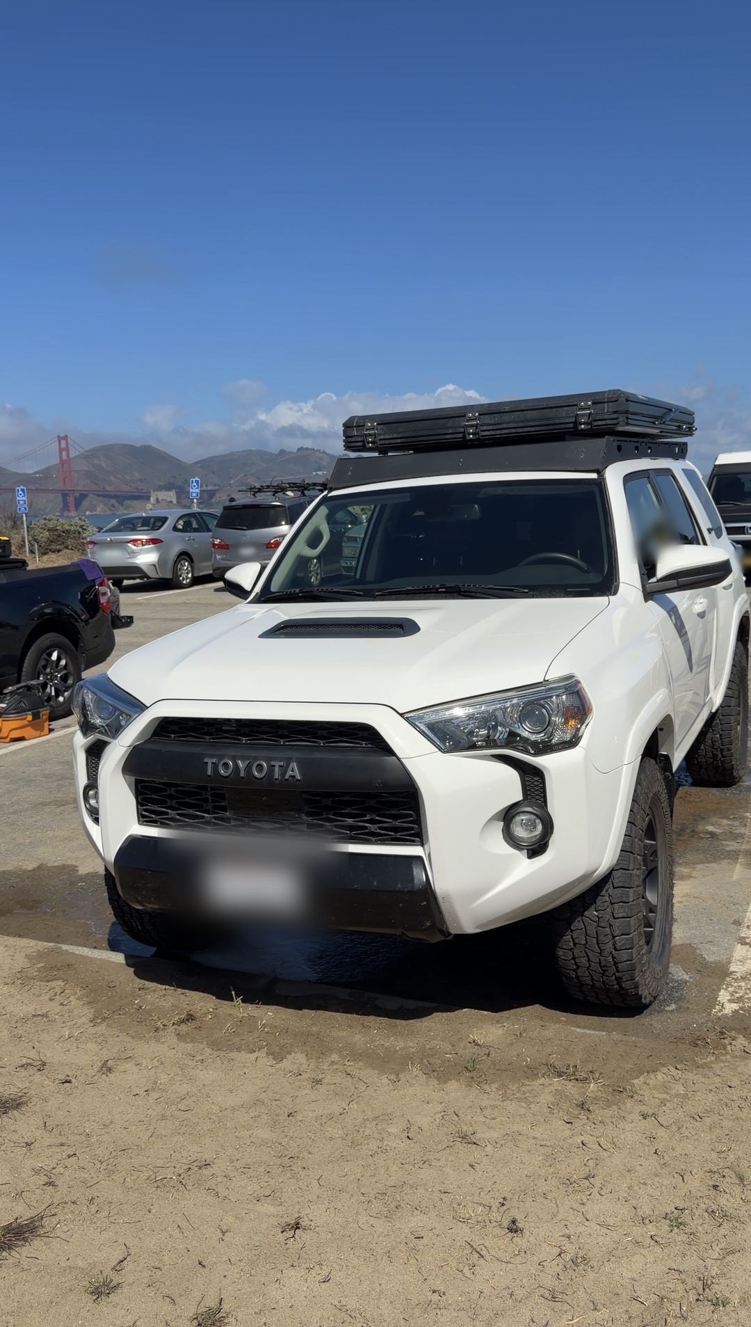 Clean white Toyota 4Runner TRD Pro with a rooftop tent, the Golden Gate Bridge in the background