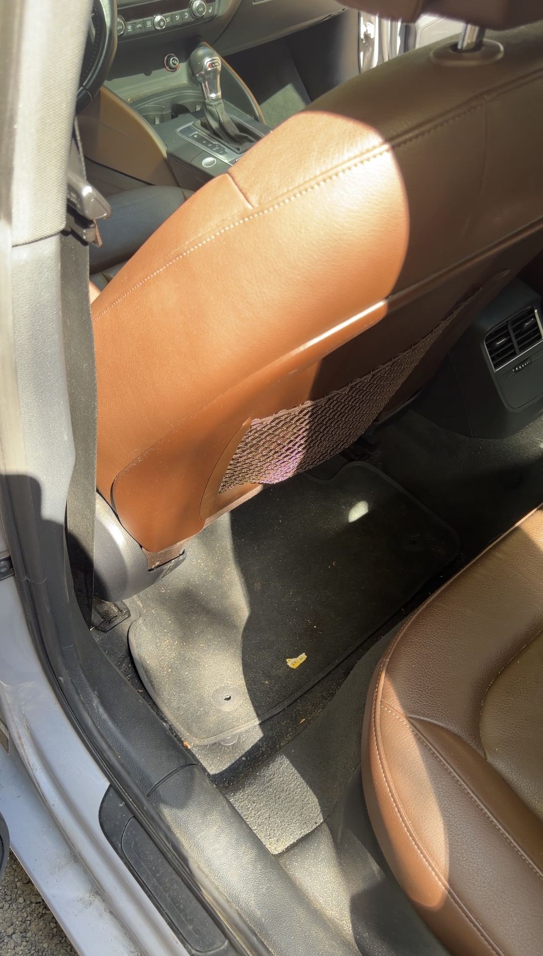 Grit and a wrapper scrap on the rear floor mat behind the driver seat of an Audi A3