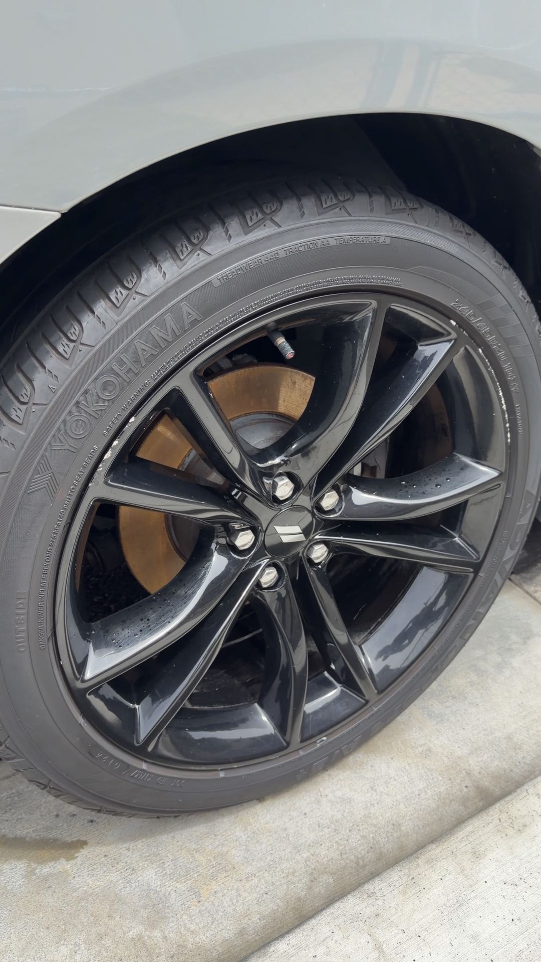 Clean black Dodge Charger wheel with water droplets and a Yokohama tyre after washing