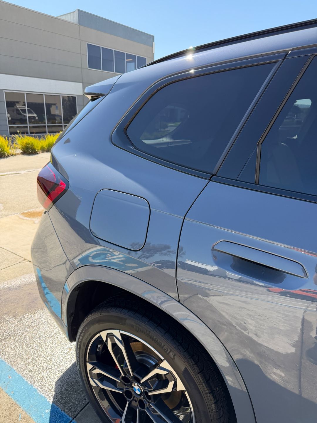 Grey BMW X1 after a wash, glossy right rear quarter in the sun