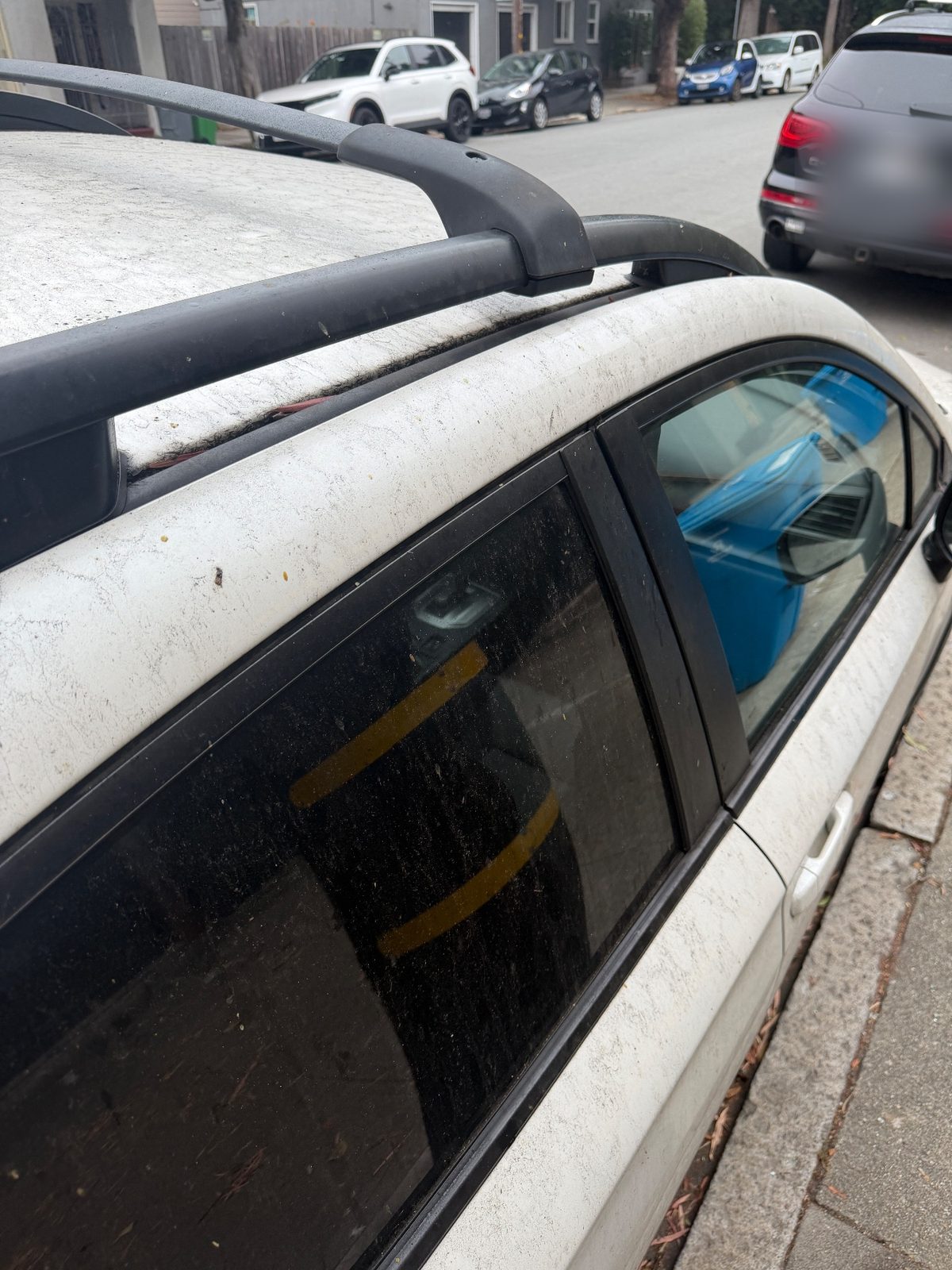 Dirty roof rail and window trim of a white Subaru Crosstrek before cleaning