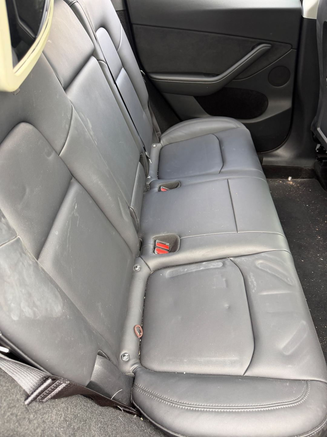 Rear bench seat of a black Tesla Model Y before detailing