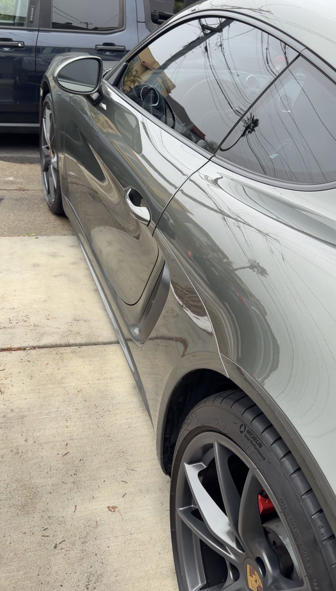 Glossy driver's-side flank of a green Porsche 718 Cayman S after a mobile detail.