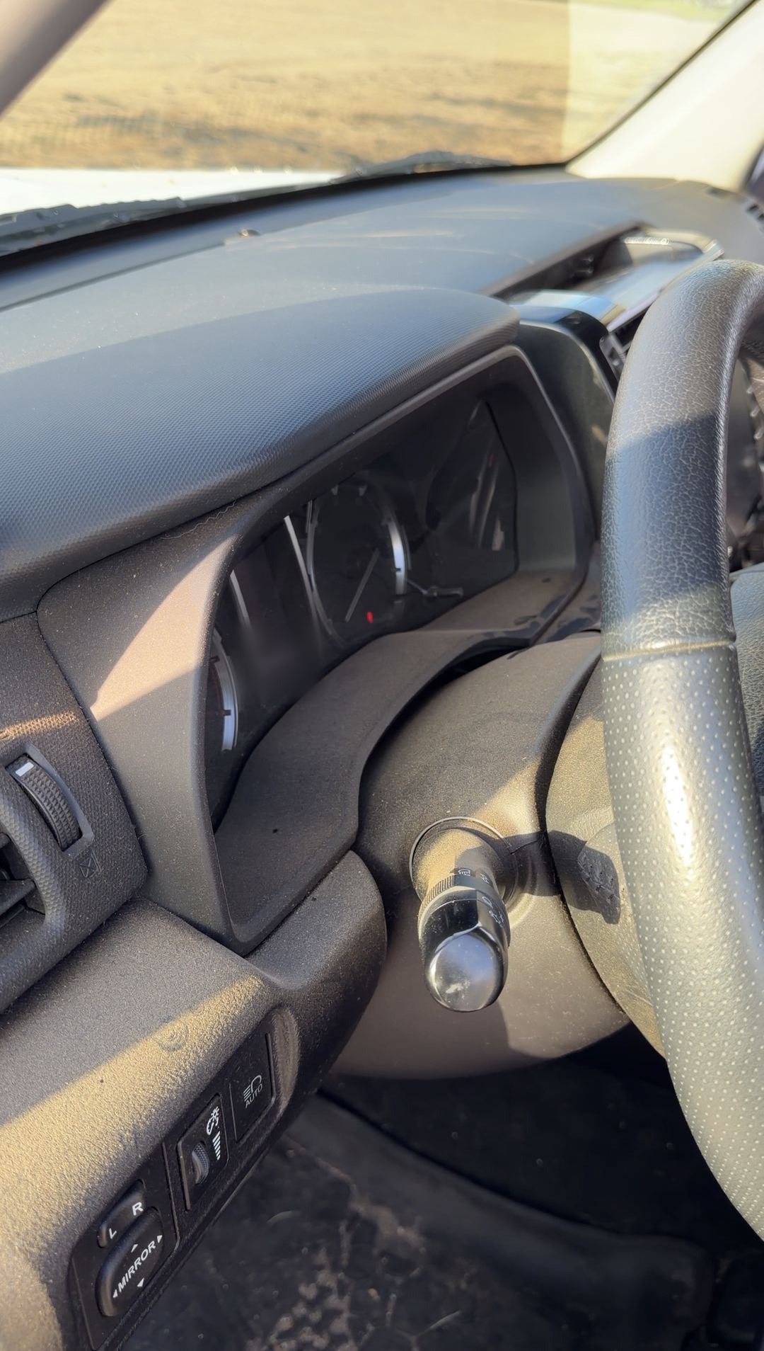 Thick dust on the dashboard, gauge hood and steering wheel of a Toyota 4Runner