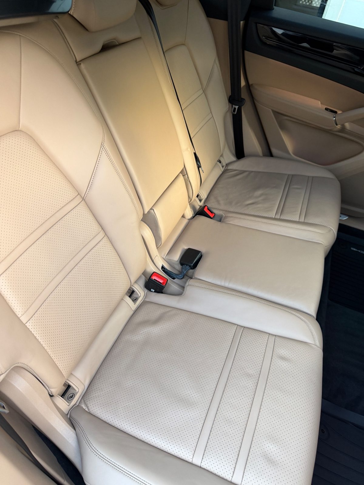 Clean rear seat of a Porsche Cayenne after detailing, tan leather cushions bright and even