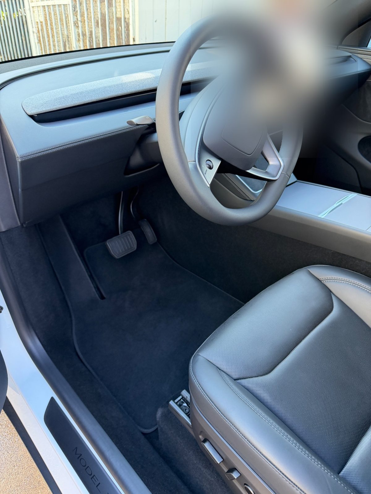 Clean driver footwell of a white Tesla Model Y after vacuuming
