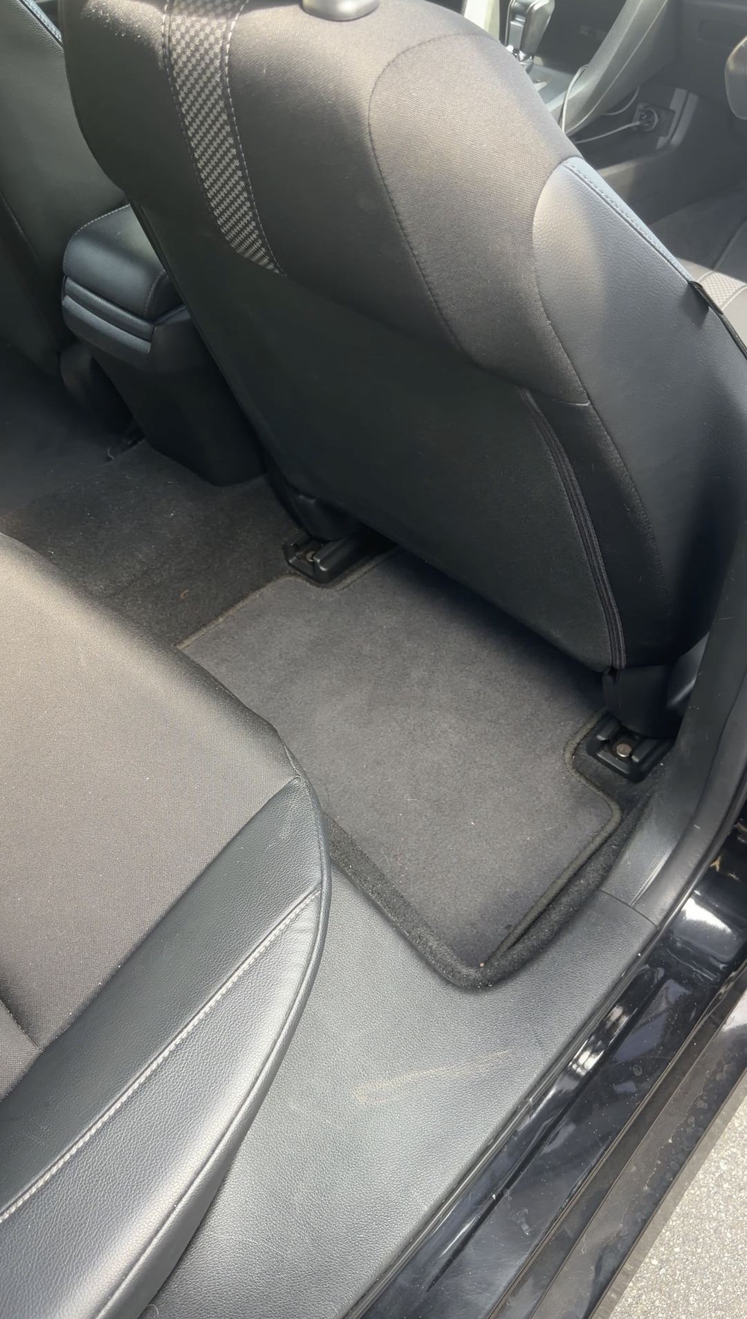 Dirty rear floor mat of a Honda Civic before vacuuming