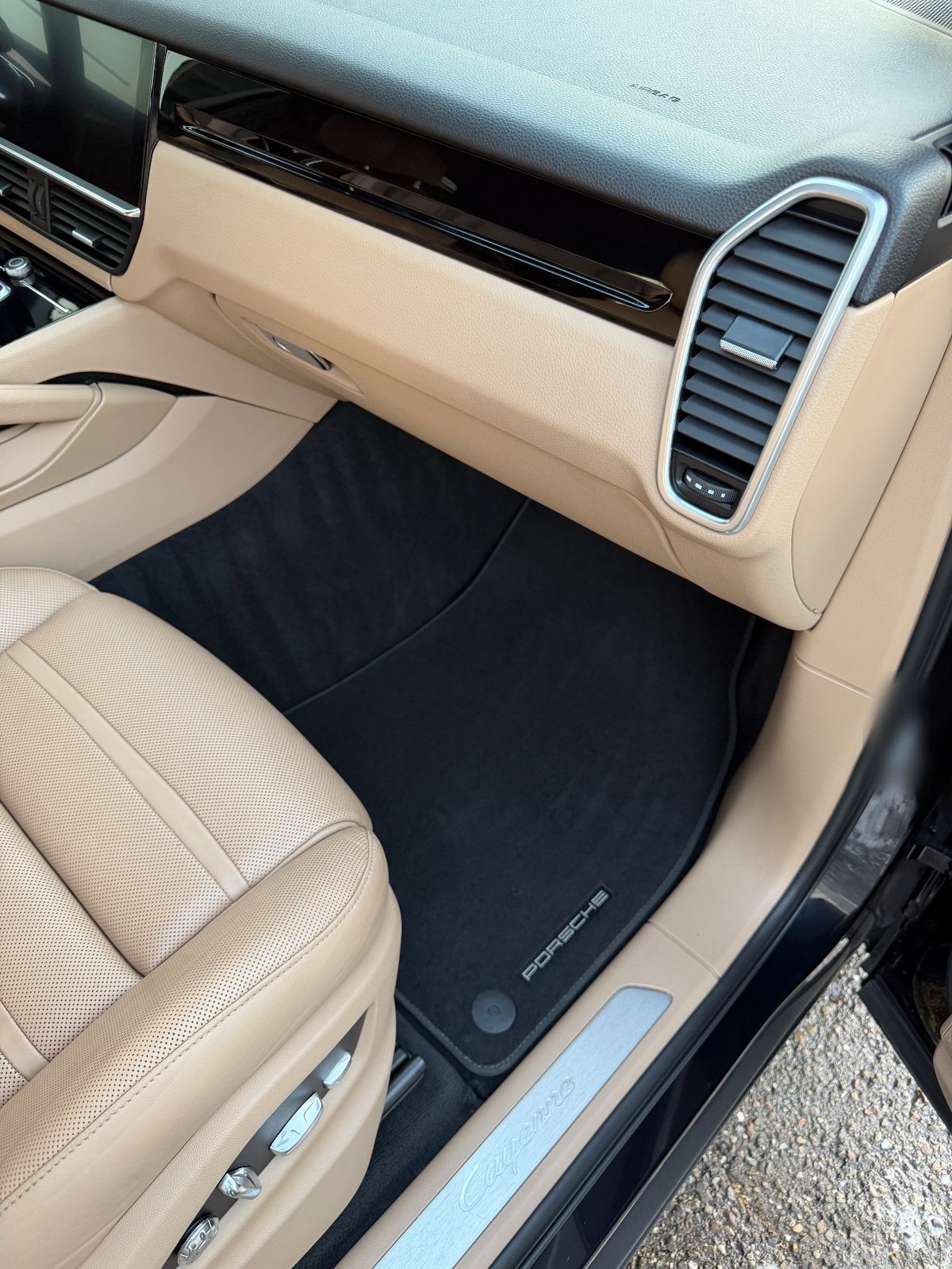 Clean passenger footwell of a Porsche Cayenne after detailing, carpet mat vacuumed and sill plate wiped