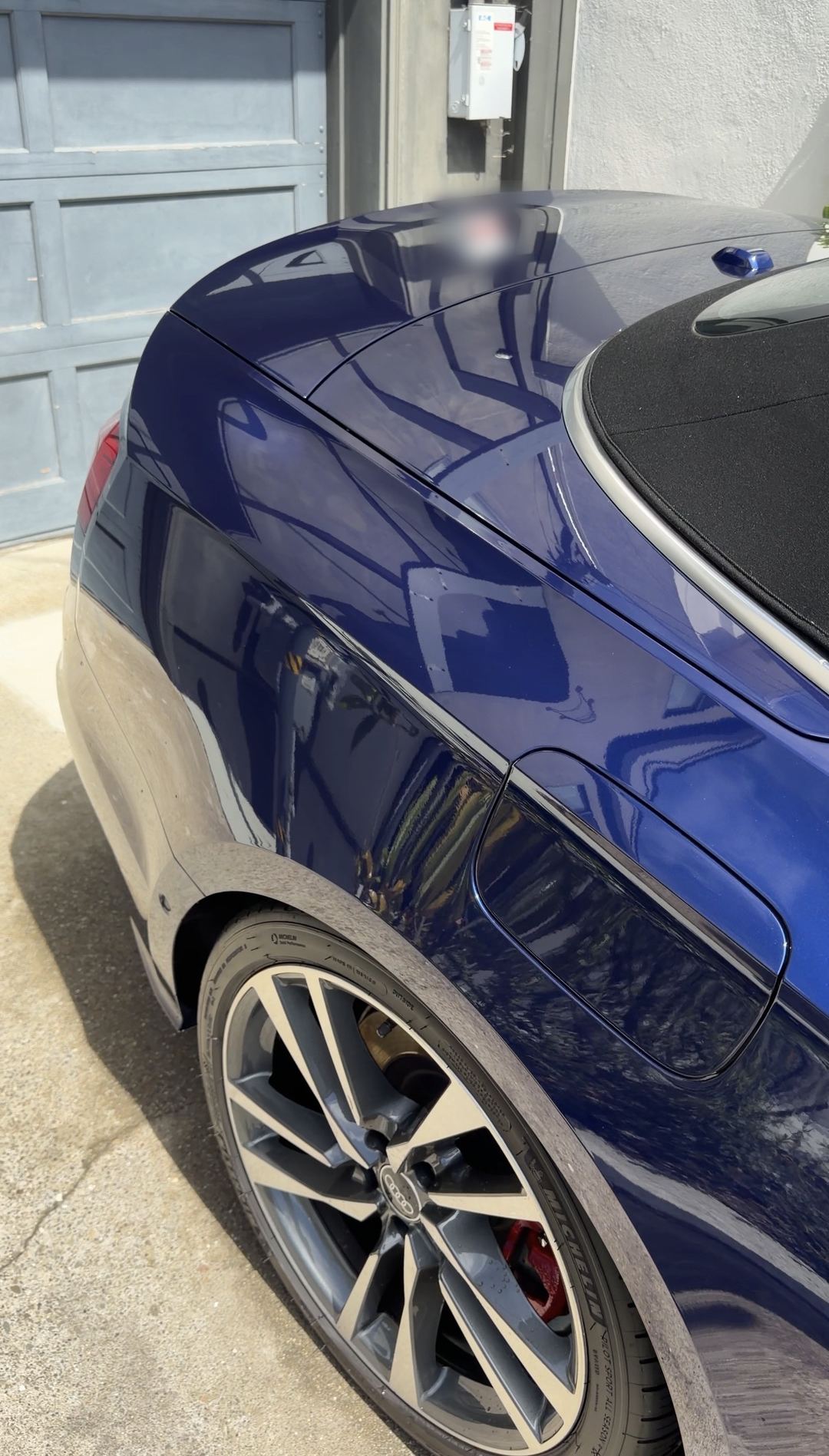 Glossy blue rear quarter and decklid of an Audi S5 Cabriolet with a red brake caliper