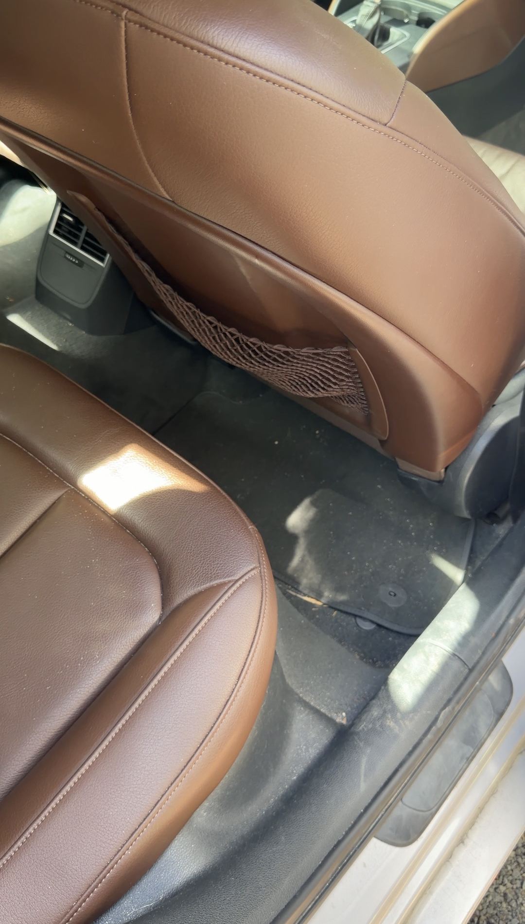 Dust and leaf bits on the rear floor mat behind the front passenger seat of an Audi A3