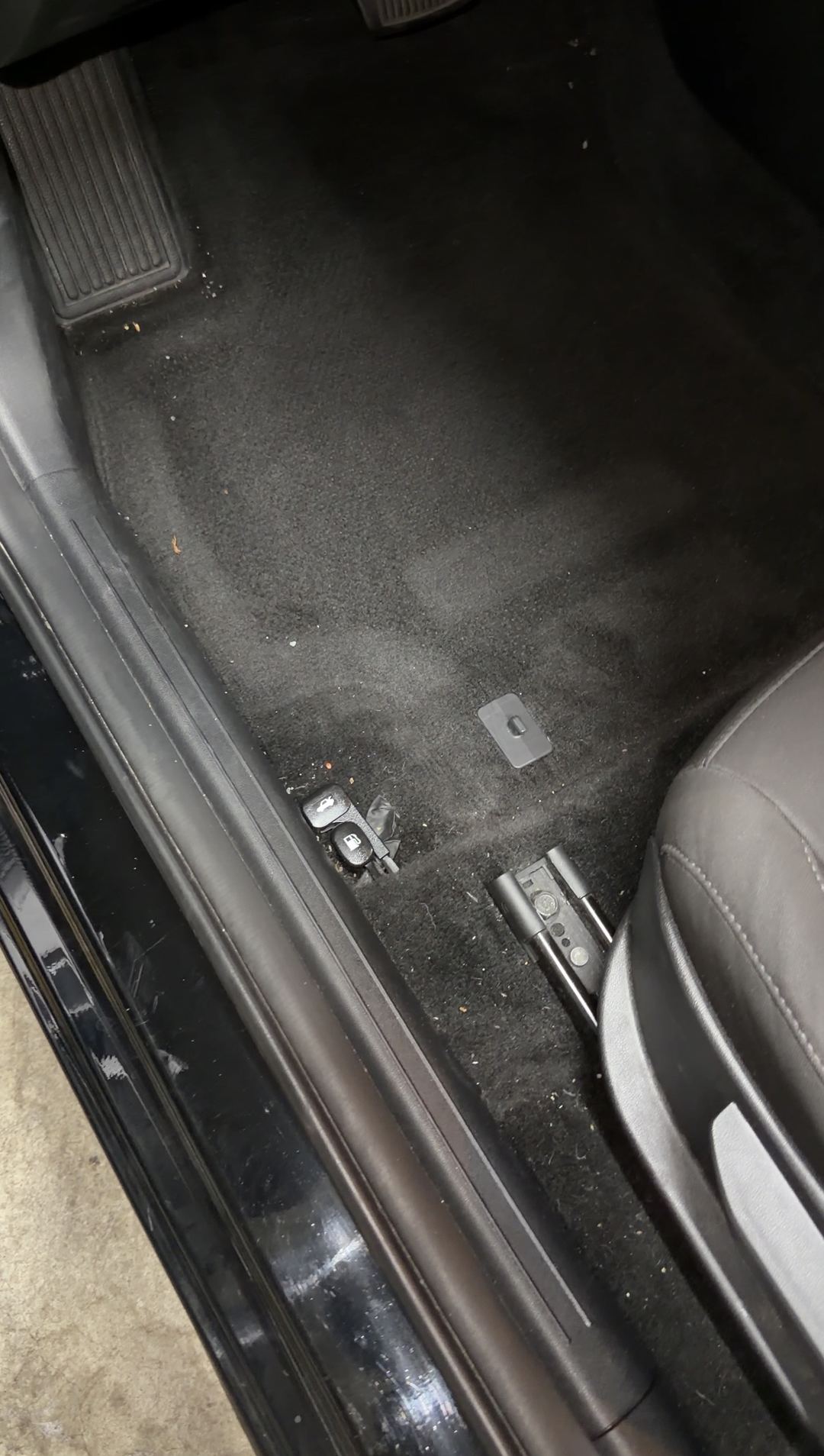 Driver footwell carpet of a Hyundai Elantra with lint and dust, floor mat removed
