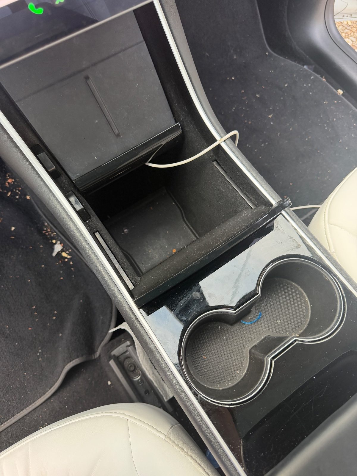 Centre console tray and cupholder of a white Tesla Model Y before detailing, with crumbs and dust