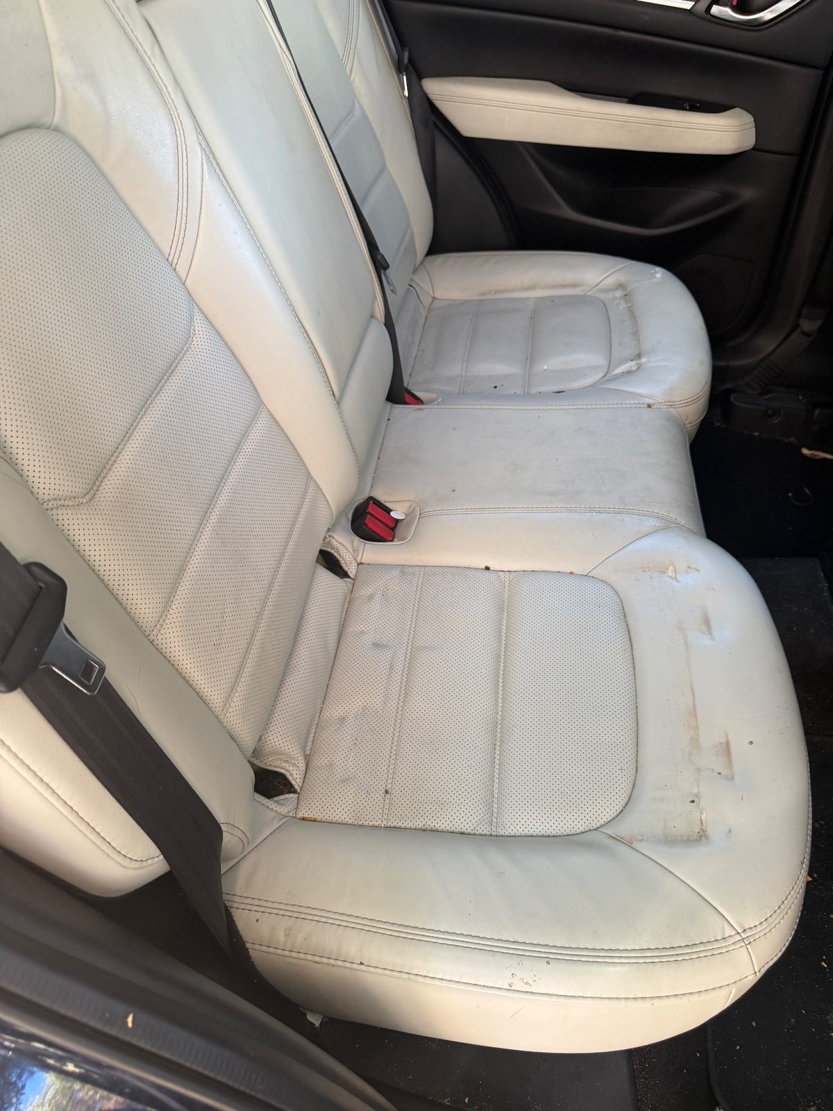 Rear seat of a dark blue Mazda CX-5 before cleaning, leather bases stained and spotted
