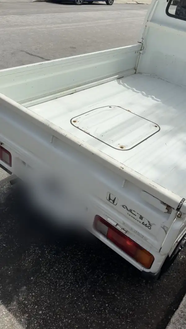Close view of a Honda Acty kei truck tailgate showing the Honda badge and ACTY 12 VALVE 660 script above a clean cargo bed.