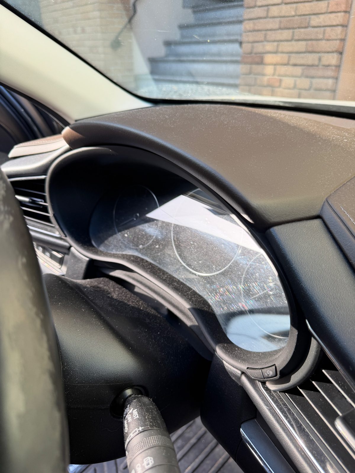 Instrument cluster of a grey Mazda CX-30 before cleaning, glass hazy with dust