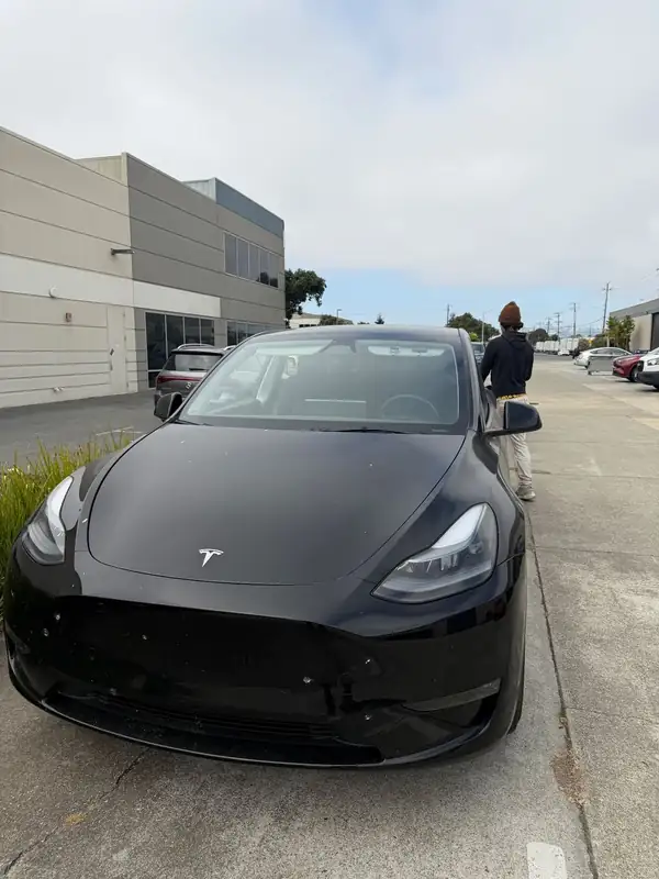 Black Tesla Model Y parked in a business-park lot before its detail