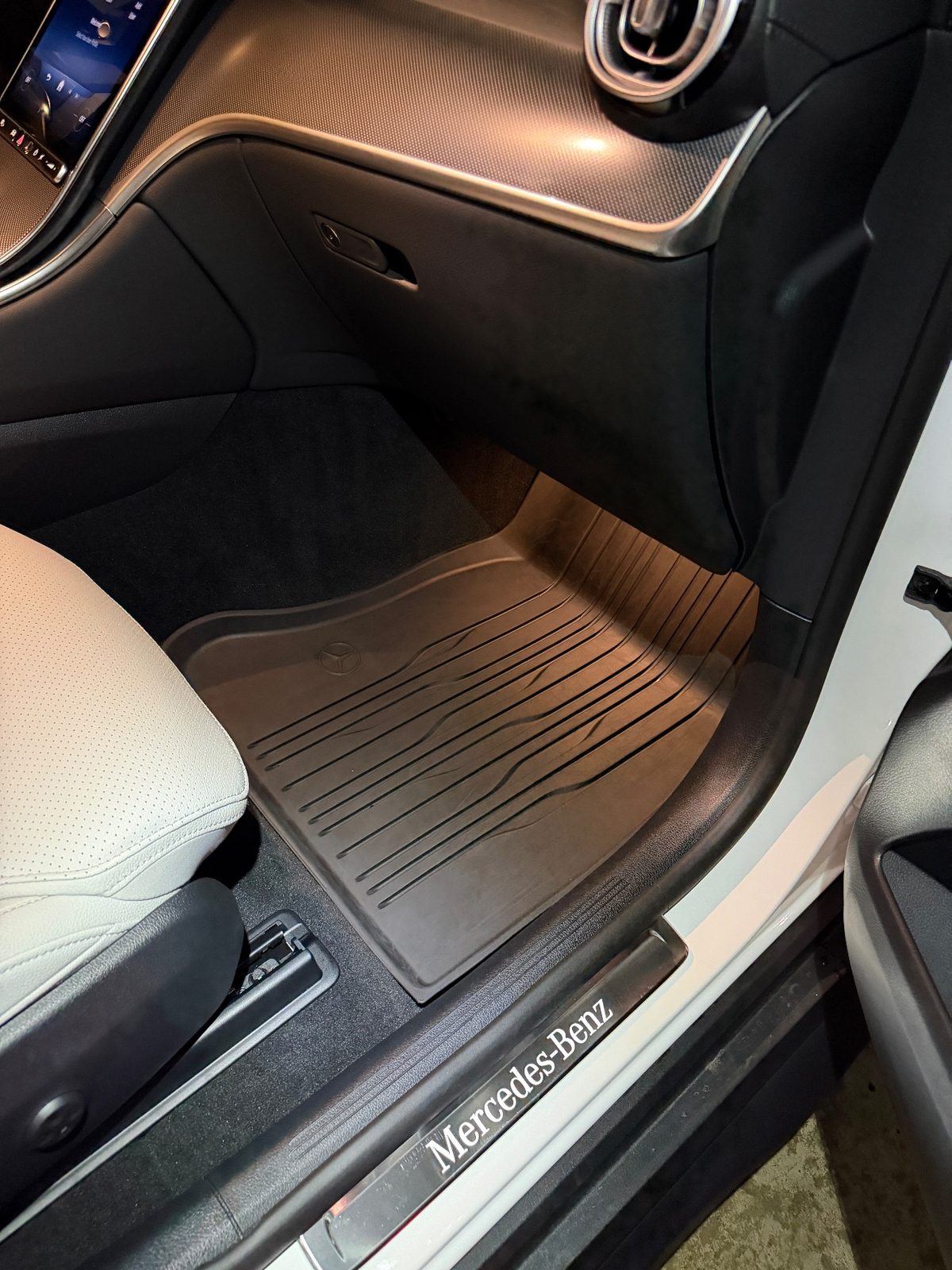 Front passenger footwell of a white Mercedes GLC after detailing, clean rubber mat and sill
