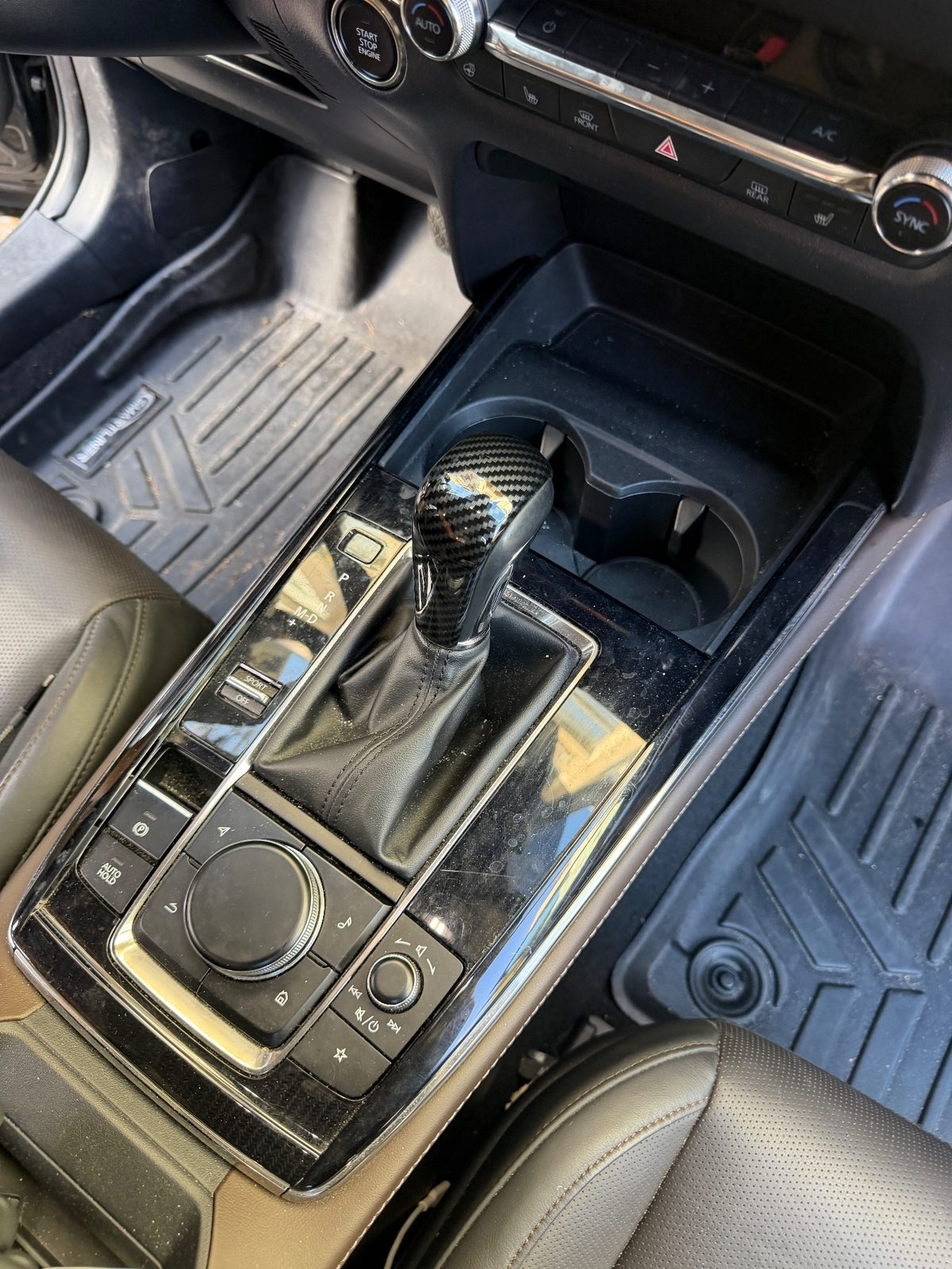 Centre console of a grey Mazda CX-30 before cleaning, gloss trim dusty and specked